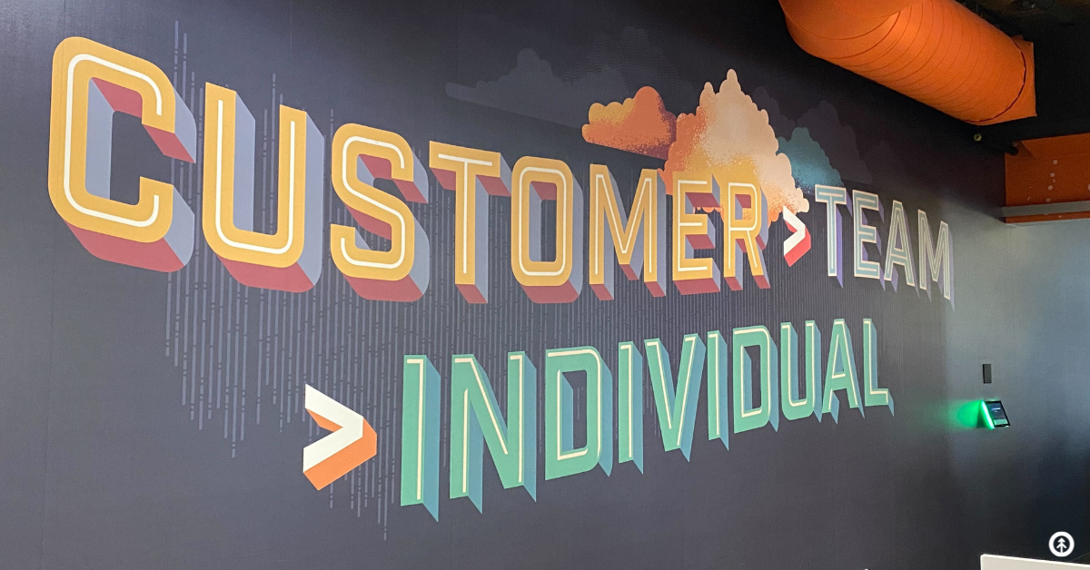 HubSpot mural on the wall at HubSpot HQ in Boston that reads customer over team over individual.