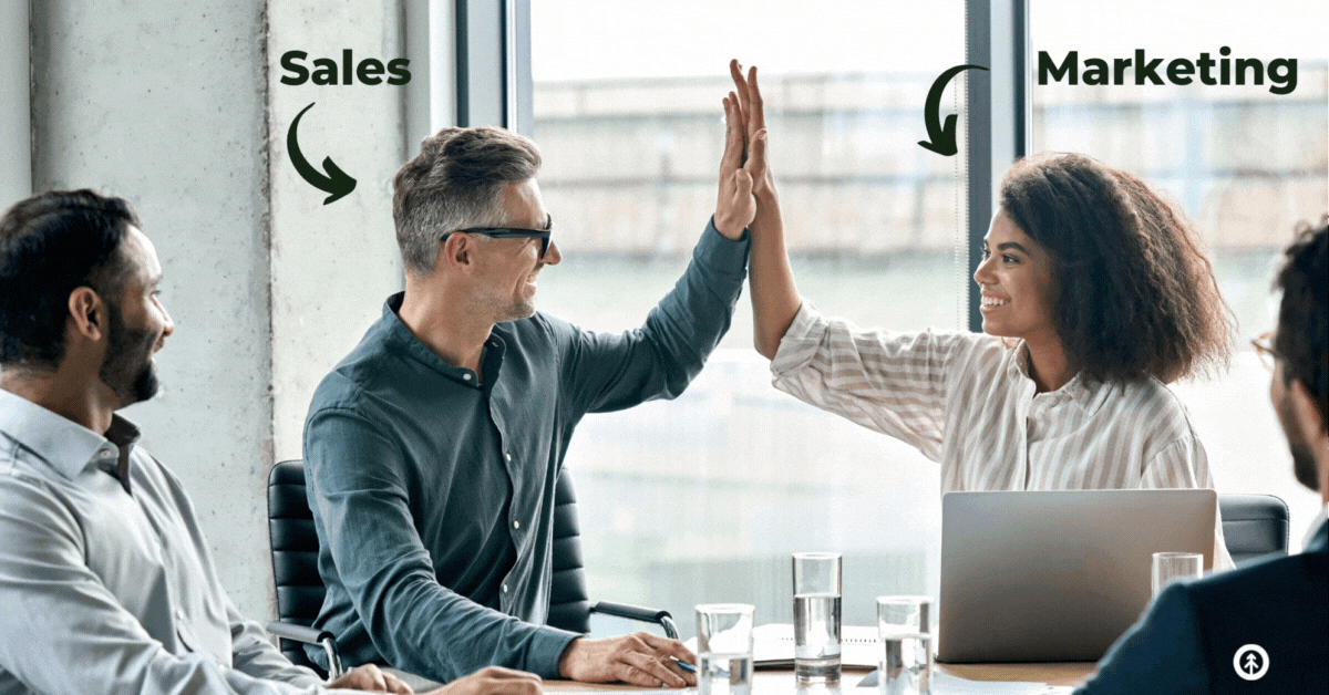 A sales person and a marketing professional high-five during a meeting. 