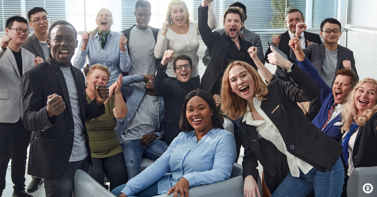 An excited group of people on a business team sitting in a business setting celebrating together. 