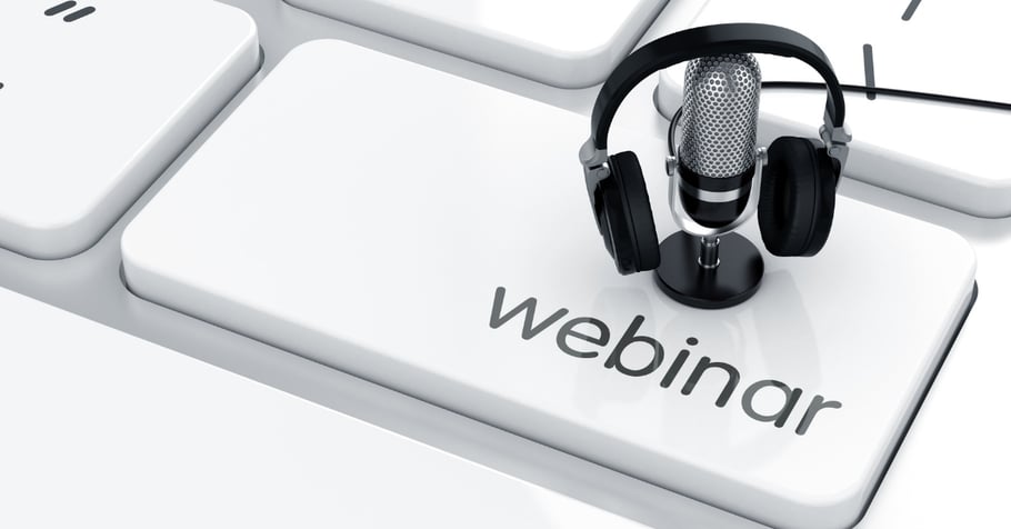 A webinar with numerous attendees blurred on a computer screen with a microphone in the forefront