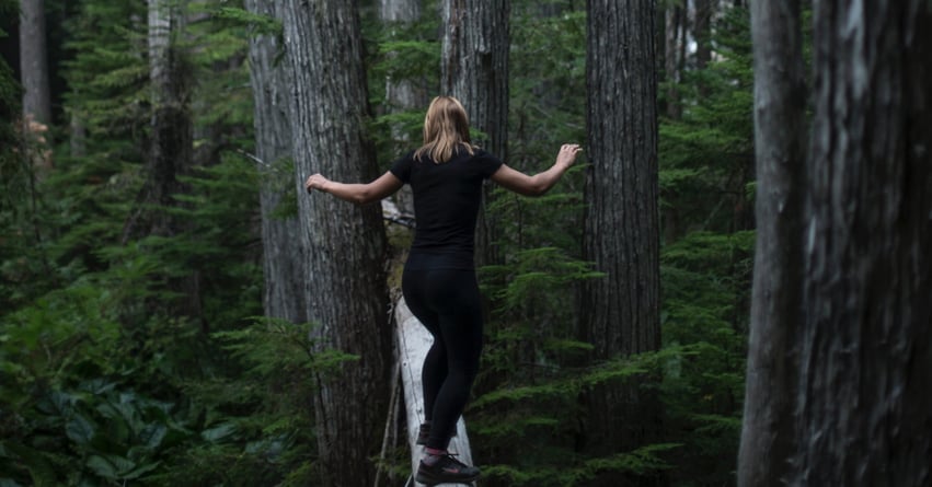 A woman balancing on a board in a forest
